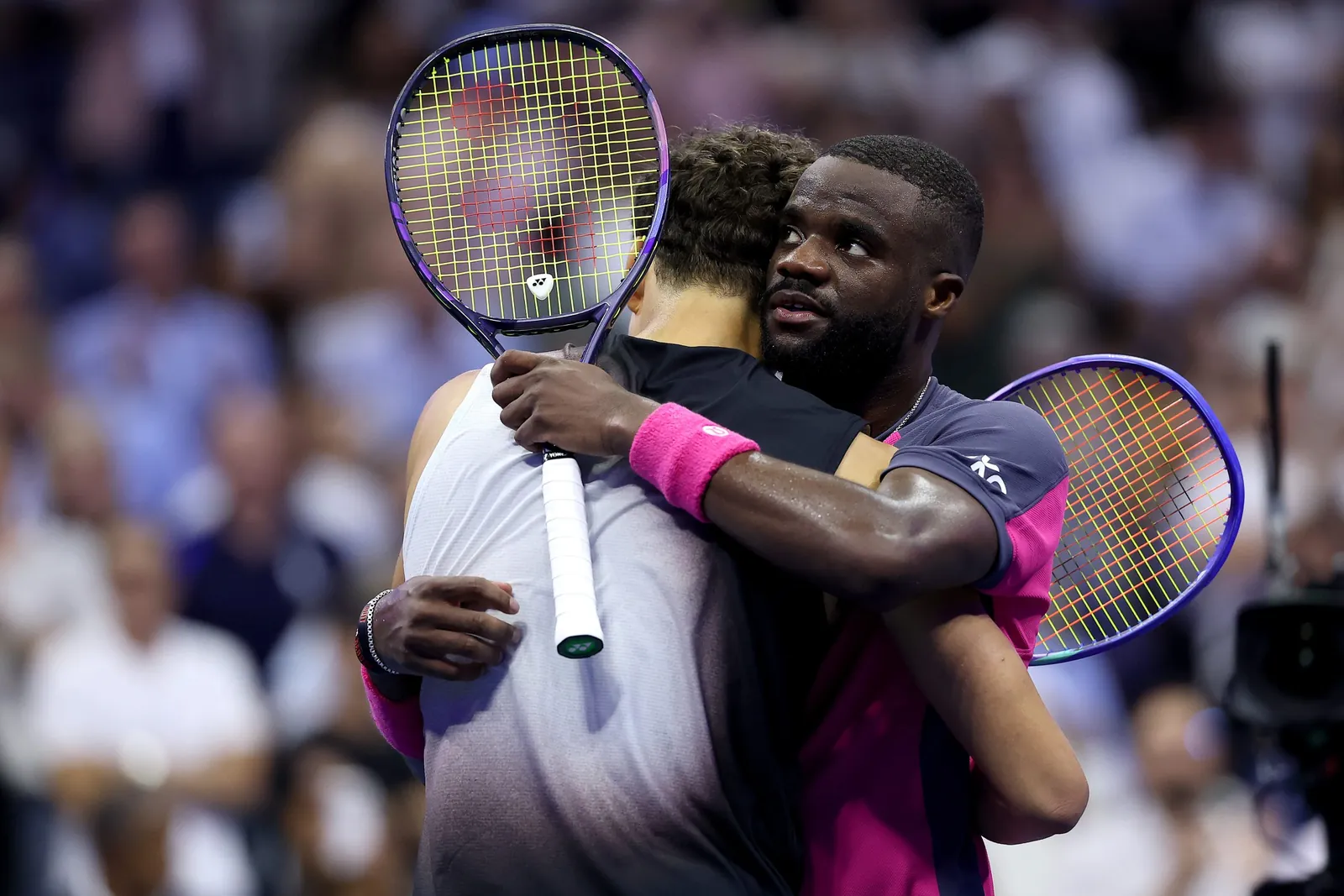 Ben Shelton and Frances Tiafoe embrace holding their tennis rackets.